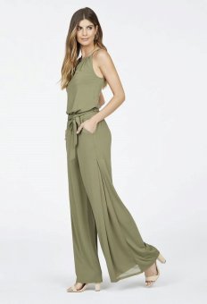 a lady putting on an olive-coloured broad knee jumpsuit and heeled sandals.